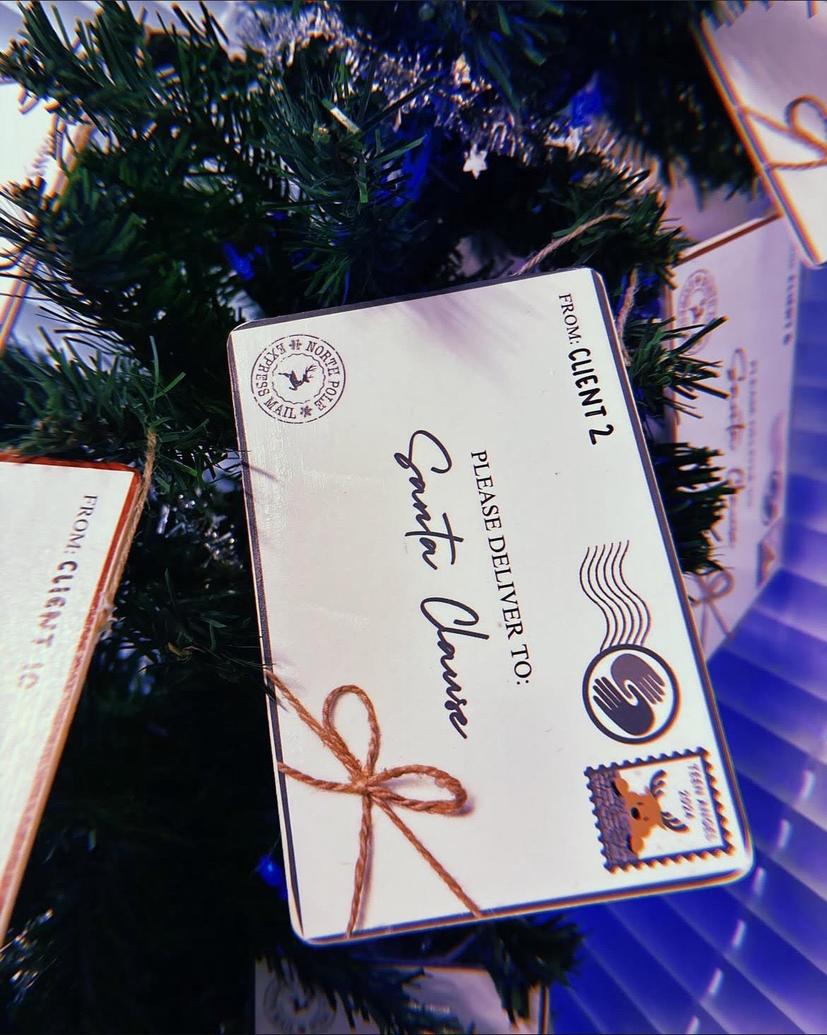 Envelope-style ornament on a Christmas tree addressed to Santa Clause.